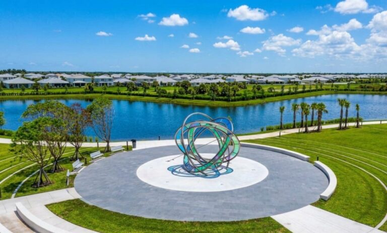 Elevated aerial view of the Stars & Stripes Park plaza layout, highlighting the tiered concrete amphitheater seating and concentric circular paver rings surrounding the central sculpture.