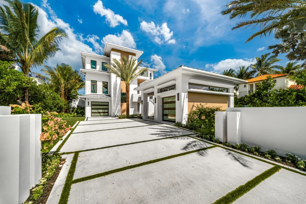 Custom concrete driveway with sandblasted shell broadcast finish leading to a modern luxury home