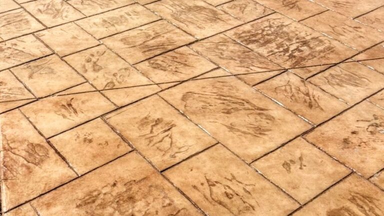Tan stamped concrete patio with square tile patterns and subtle engraved texture.